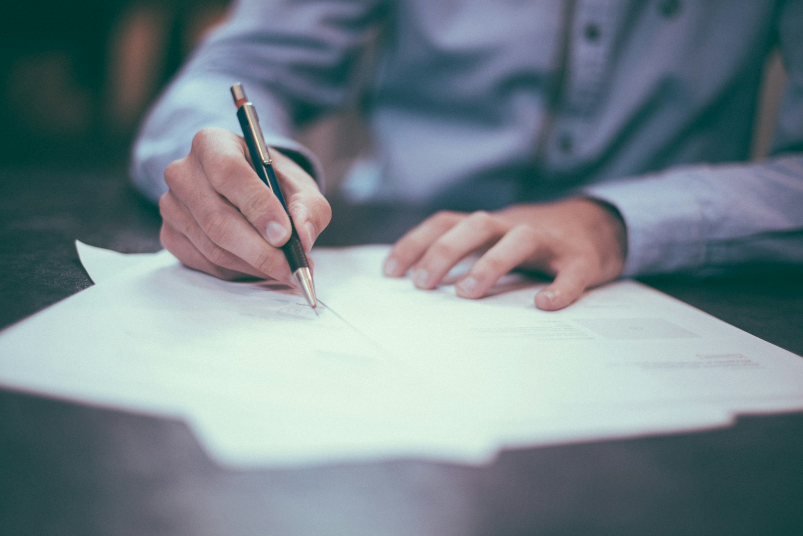 Persona firmando un documento legal sobre un escritorio